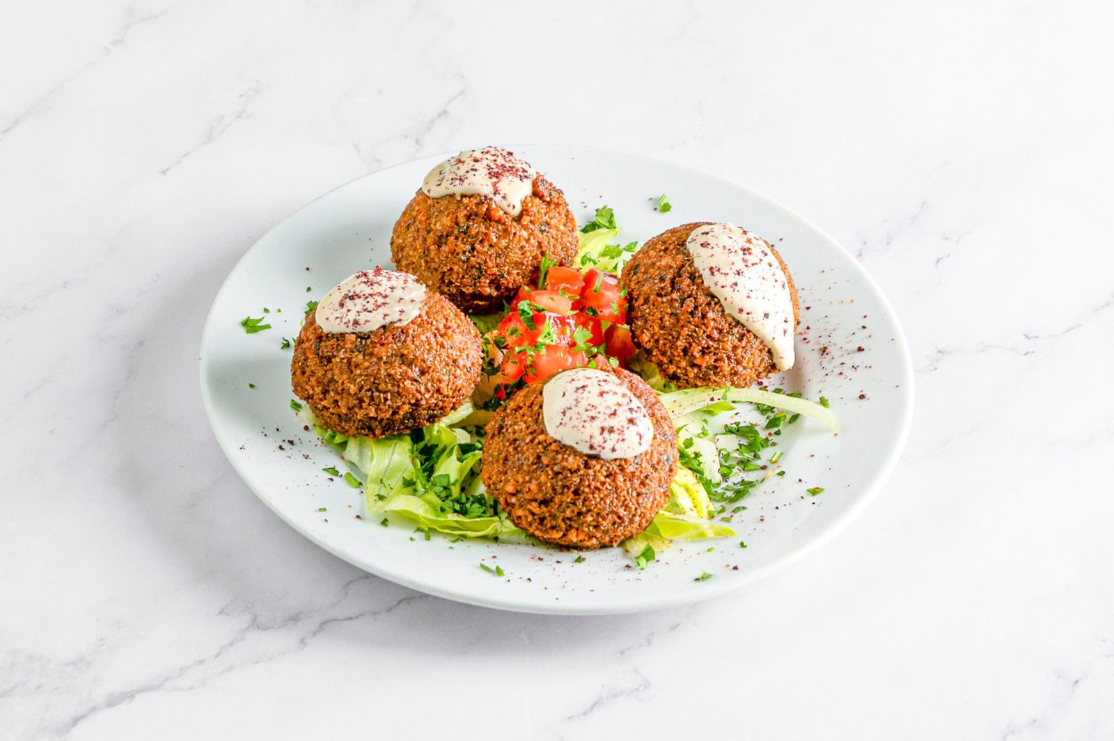 Falafel crujiente con salsa tahini sobre ensalada fresca